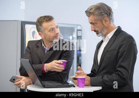 Due giovani imprenditori aventi il caffè usando un computer portatile Foto Stock