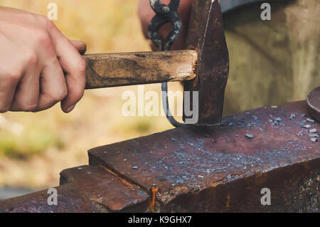 Fabbro forges dettaglio. fabbro lavorare all'esterno. master lavora sull'incudine. martello di forgiatura di strutture metalliche all'aria aperta in natura. a Hamm Foto Stock