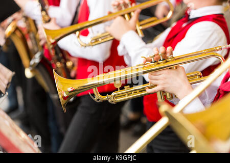 Prestazioni del jazz band concetto - closeup ensemble di musicisti di suonare alle trombe e sassofoni in concerto rosso costumi, mani maschio con scintillante equ Foto Stock