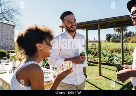 Sorridente giovane donna avente una festa con gli amici. Amici godendo di partito nel giardino del ristorante. Foto Stock