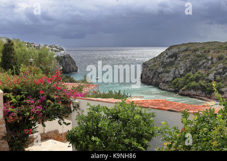 I minorchini resort di Cala en Porter nel mar mediterraneo con nuvole temporalesche Foto Stock