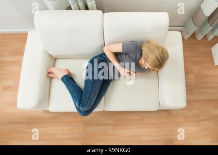 Giovane donna sul divano affetti da stomachache Foto Stock