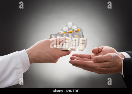 Close-up di un medico la mano dando vari farmaci per il paziente Foto Stock