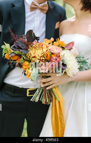 Le relazioni, celebrando e concetto di caduta. C'è un meraviglioso paio di amanti, sposa e il suo fidanzato, vestito in Wedding moderna costumi con grande mazzo di fiori delicati strapped soleggiata con nastro giallo Foto Stock