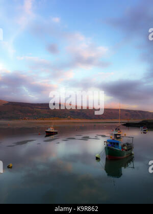 Barche su acque calme di barmouth in Galles come approcci al tramonto. Foto Stock