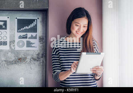 Asian business owner usura panno casuale utilizzando tablet in home office e spazio di lavoro per contattare il cliente sul canale online,office lifestyle con technolo Foto Stock