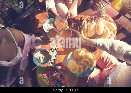 Vista dall'alto di persone toast bicchieri di succo mentre si consuma la prima colazione insieme il giovane e la donna in mattinata sedere al tavolo con i fiocchi d'avena e frutta fresca Foto Stock