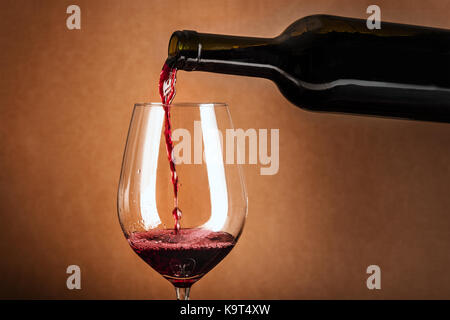 Vino rosso versato in vetro dalla bottiglia Foto Stock