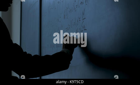 Scienziato scrivere formule sulla lavagna. mano con chalk ha scritto le formule di fisica sulla lavagna nera closeup Foto Stock