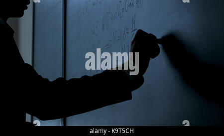 Scienziato scrivere formule sulla lavagna. mano con chalk ha scritto le formule di fisica sulla lavagna nera closeup Foto Stock