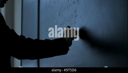 Scienziato scrivere formule sulla lavagna. mano con chalk ha scritto le formule di fisica sulla lavagna nera closeup Foto Stock