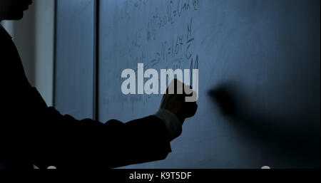 Scienziato scrivere formule sulla lavagna. mano con chalk ha scritto le formule di fisica sulla lavagna nera closeup Foto Stock