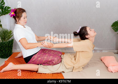 Donna asiatica getting tradizionale Thai massaggio stretching dal terapista Foto Stock