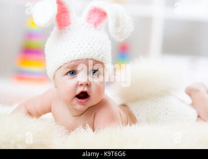 Sorridente simpatico baby in costume coniglietto giacente su fur in vivaio Foto Stock