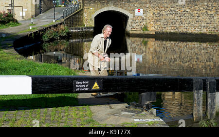 Uomo di blocco apertura cancello a Rochdale Canal a Sowerby Bridge, Calderdale, West Yorkshire, Inghilterra, Regno Unito Foto Stock