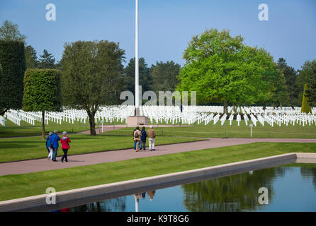 I visitatori a piedi attraverso il perfettamente curato giardino e linee di croci al cimitero americano di Colleville-sur-mer, Normandia francia Foto Stock