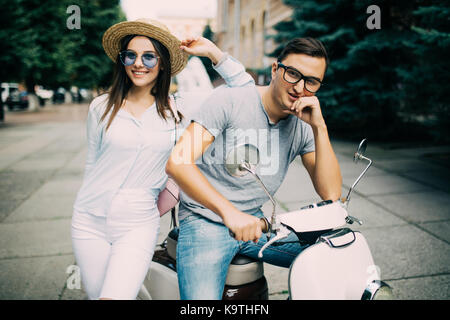 Bella giovane seduto su uno scooter insieme nella strada di città Foto Stock