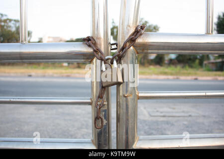 Lucchetto dorato con catena utilizzata su un opaco recinto. messa a fuoco selettiva è utilizzare sul lucchetto. Foto Stock