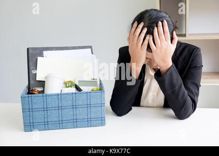 Tristezza bella femmina lavoratore di ufficio è sparato imballaggio oggetti personali seduto sulla scrivania sensazione sconvolto e pensare in futuro posto di lavoro Foto Stock