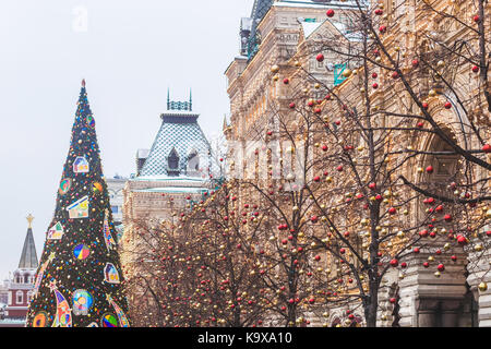 Strade completamente decorato per il Natale con il rosso e oro sfere. Albero di natale in città. casa illuminata con un sacco di luci. Foto Stock
