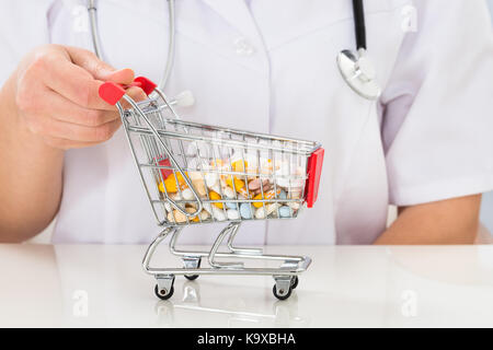 Close-up di medico donna con carrello pieno di pillole al banco Foto Stock
