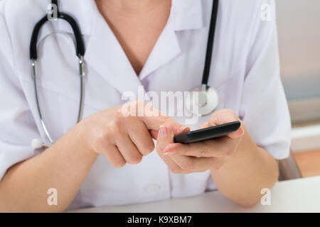 Close-up di medico con stetoscopio utilizzando il telefono cellulare Foto Stock