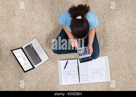 Angolo di alta vista della giovane donna il calcolo di fatture a casa Foto Stock