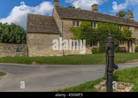 La pompa dell'acqua sul villaggio verde a poca Barrington, Gloucestershire Foto Stock