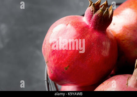 Ripe rosso melograno in vintage cestello di metallo sulla pietra scura sullo sfondo autunno autunno ringraziamento spazio di copia Foto Stock