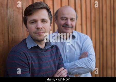Padre e figlio di stare in piedi insieme vicino a sfondo di legno. Foto Stock