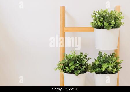 Verde artificiale di piante in un metallo bianco fioriere stand sui ripiani in legno per la casa e arredamento per ufficio senza la cura. Foto Stock