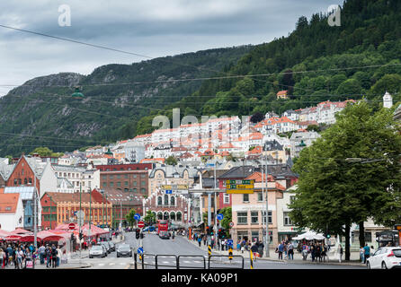 La famosa città di Bergen con case costruite sulle colline e i turisti a piedi in strada per lo shopping e il mercato del pesce Foto Stock