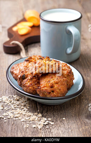 Carota e oat cookie sulla piastra di blu, una tazza di latte sul vecchio sfondo di legno Foto Stock