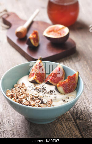 Una sana prima colazione. muesli, yogurt, fichi, chia semi in un vaso blu ha vecchio sfondo di legno Foto Stock