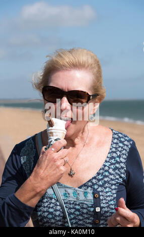 Donna al mare di mangiare un cono gelato Foto Stock