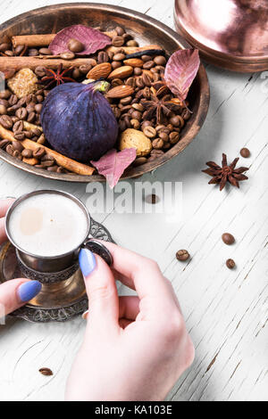 Tazza di caffè in mani femminili su un sfondo di caffè Foto Stock