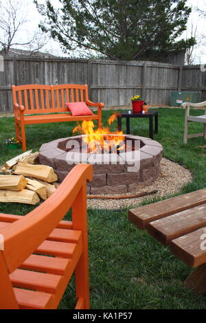 Backyard una buca per il fuoco con panche di legno riuniti intorno a Foto Stock