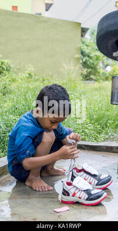 Angul, odisha, India - 3 agosto 2017: un bambino la sua pulizia scarpe in un villaggio a angul distretto di odisha stato in India. Foto Stock