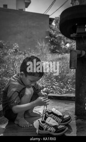 Angul, odisha, India - 3 agosto 2017: un bambino la sua pulizia scarpe in un villaggio a angul distretto di odisha stato in India. Foto Stock