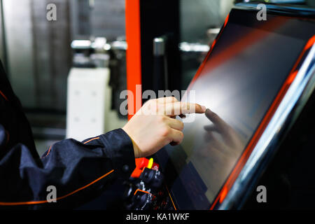 L'operatore regola moderno tornio CNC macchina utilizzando lo schermo di sfioramento. messa a fuoco selettiva. Foto Stock