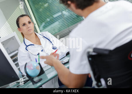 Medico consolante di un paziente disabile Foto Stock