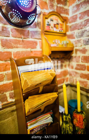 La vista laterale della carta in legno stand posto vicino alla parete di mattoni decorata con scolapasta e due candele. Foto Stock