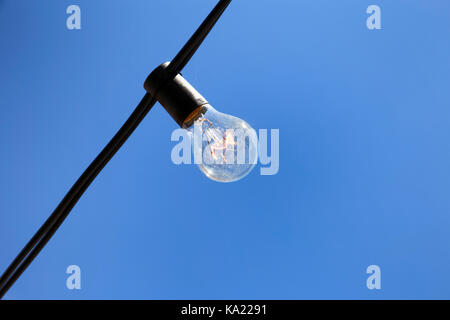 Singola lampadina sul cielo appeso sullo sfondo di un filo Foto Stock