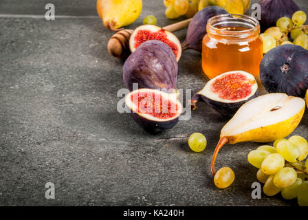 Spuntini, diete vegane dolci frutti d'autunno (figg, pere, uve) con miele su una pietra nera tabella. spazio copia Foto Stock