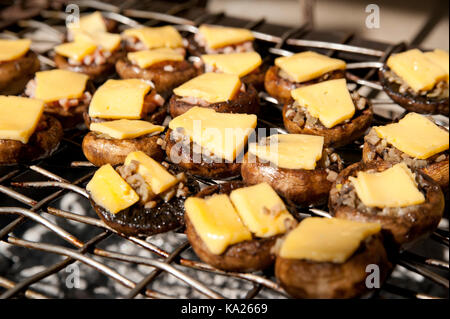 Tappi mashroom di un pulsante di funghi (Portobello) con le fette di formaggio su una parte superiore, la frittura su una griglia Foto Stock