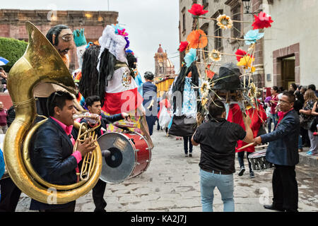 Una Marching Band segue una sfilata di carta gigante-mache marionette chiamato mojigangas in una processione attraverso la città all'inizio della settimana di festa del patrono san michele settembre 22, 2017 in San Miguel De Allende, Messico. Foto Stock