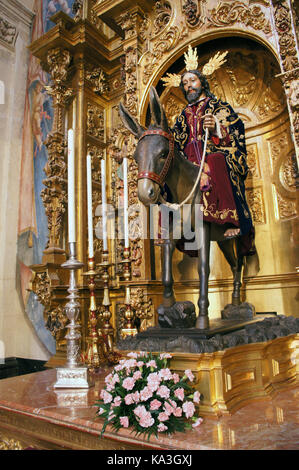 Processione di Gesù Cristo che porta croce, vestita di viola scuro con alcuni ornamenti barocchi dorati sullo sfondo Foto Stock
