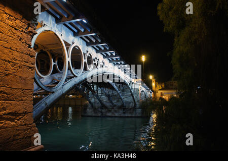 Vista notturna del Ponte di Triana (Puente de Isabela II) sul Canal de Alfonso XIII di Guadalquivir a Siviglia, Spagna Foto Stock