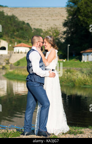 Sposa e lo sposo abbracciando emotivo di fronte a un lago Foto Stock