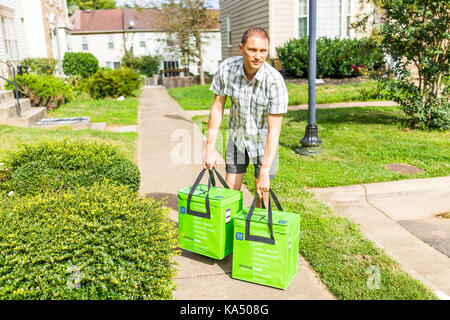 Fairfax, Stati Uniti d'America - 12 Settembre 2017: Amazon isolato fresco di consegna di generi alimentari Borse Borse sul fronte home casa portico closeup con man picking loro fino a st Foto Stock